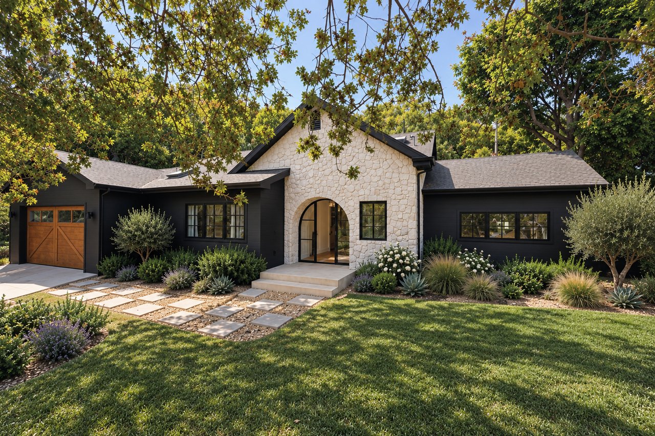 Single-story dark-sided home with a pale stone façade, arched entry, and landscaped front yard.