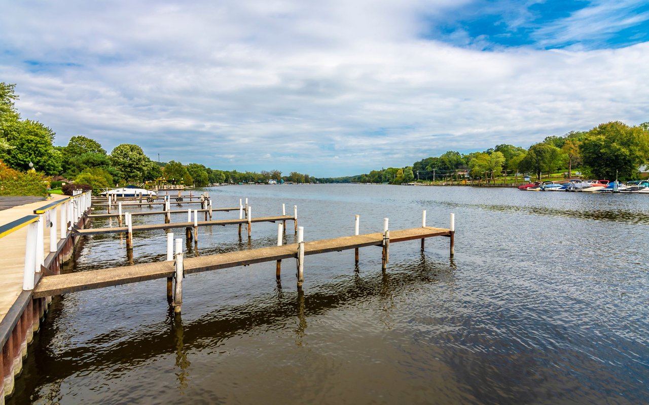 Fox River Grove riverfront with wooden docks, moored boats, and a tree-lined shore.