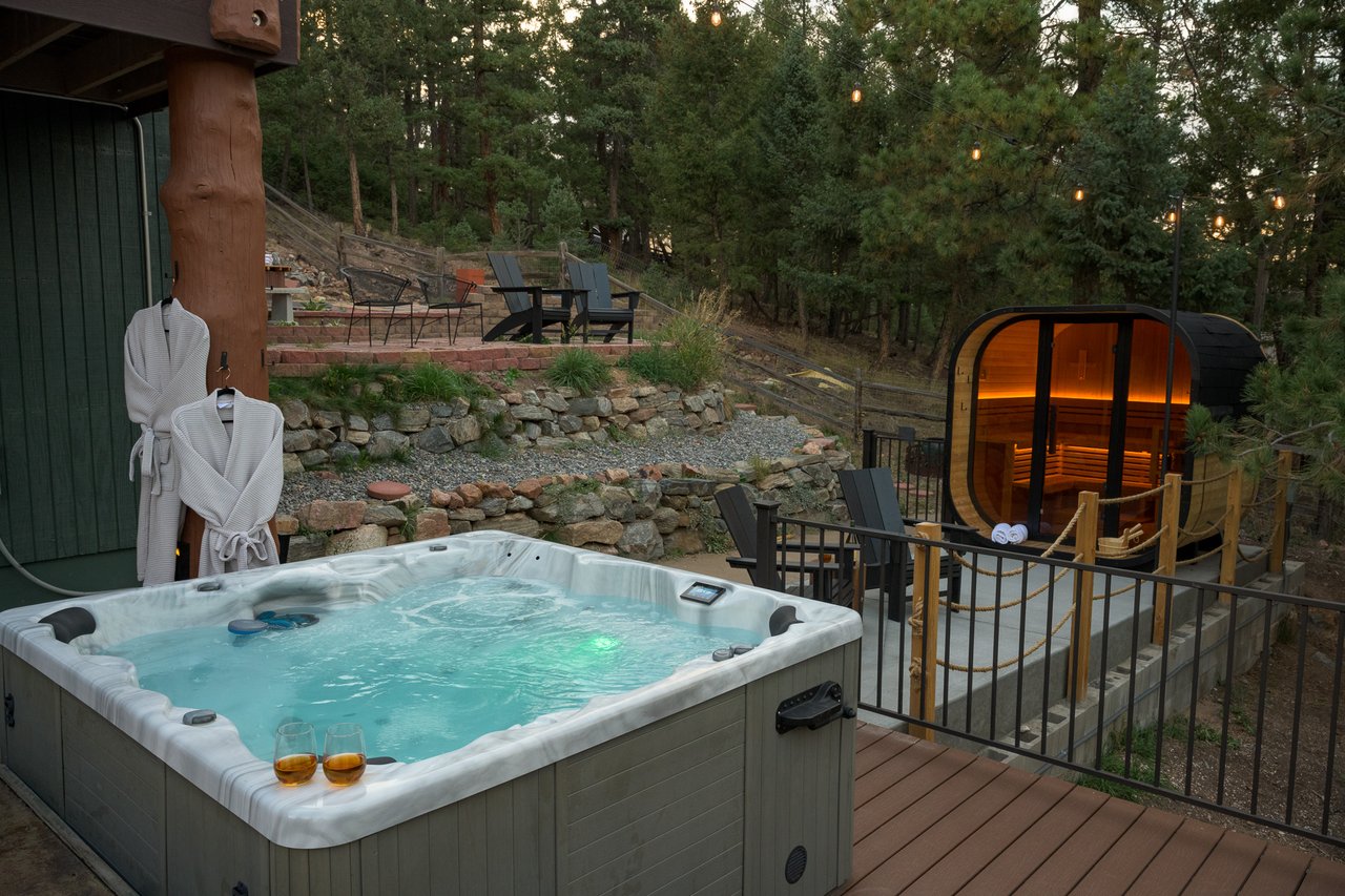 Outdoor hot tub and illuminated barrel sauna on a wooded deck