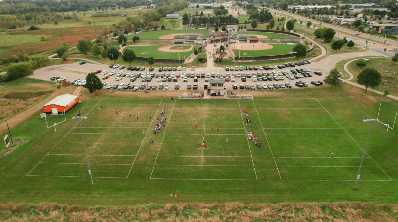Aerial view of a vibrant sports complex in Verona, WI, featuring active multi-use fields and baseball diamonds, showcasing the exceptional community amenities and outdoor recreation spaces available to local homeowners.