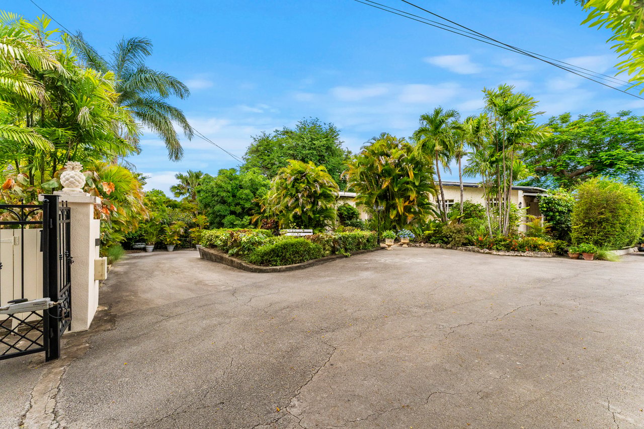Haven View entrance with a gated driveway and lush tropical landscaping.