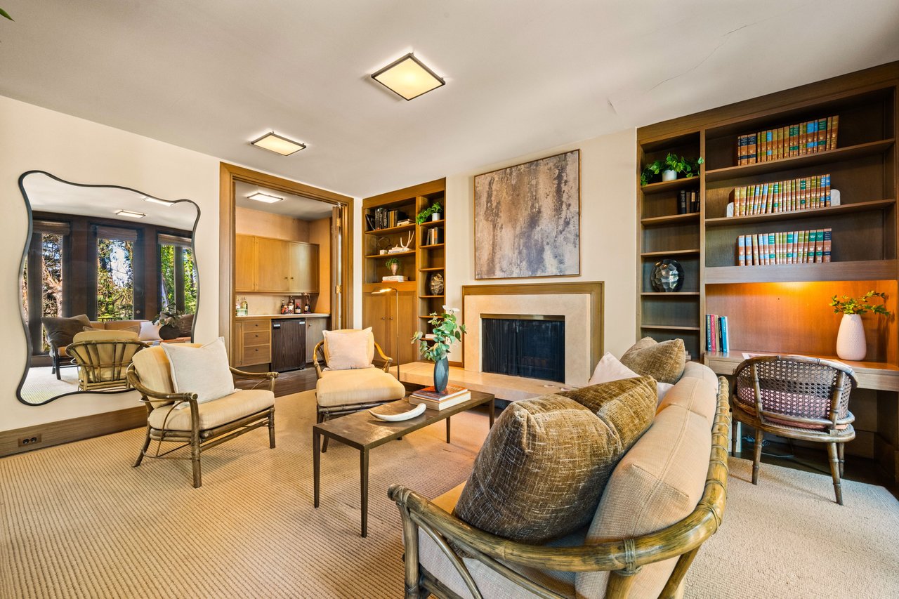 Living room with a fireplace, built-in bookcases, and neutral seating.