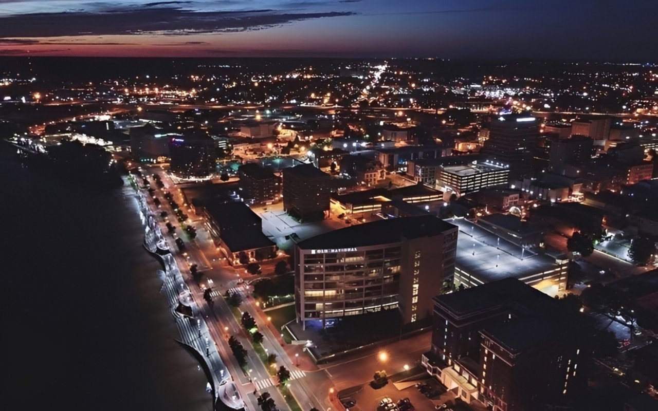 Downtown Evansville at dusk, with illuminated riverfront streets and the Old National building.