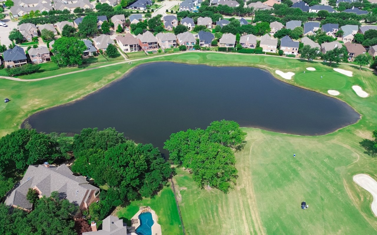 Aerial view of homes along a golf course surrounding a large pond.