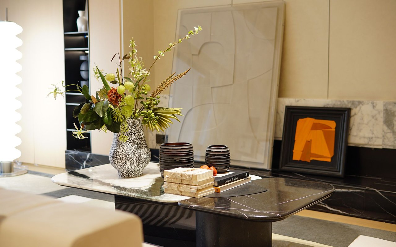 Living room with a marble coffee table, floral arrangement, and black fireplace.