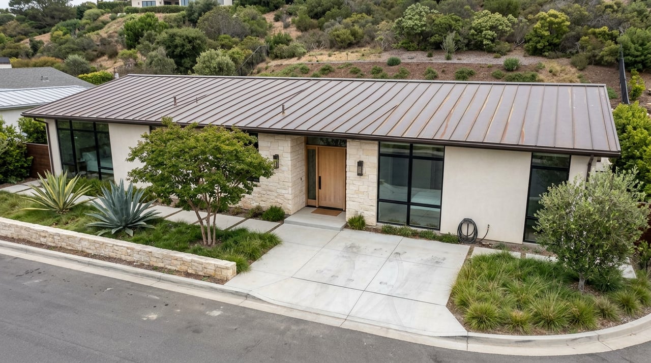 Coastal modern home with limestone entry, pale stucco, broad dark-framed windows, and a sculptural agave beside the walkway.