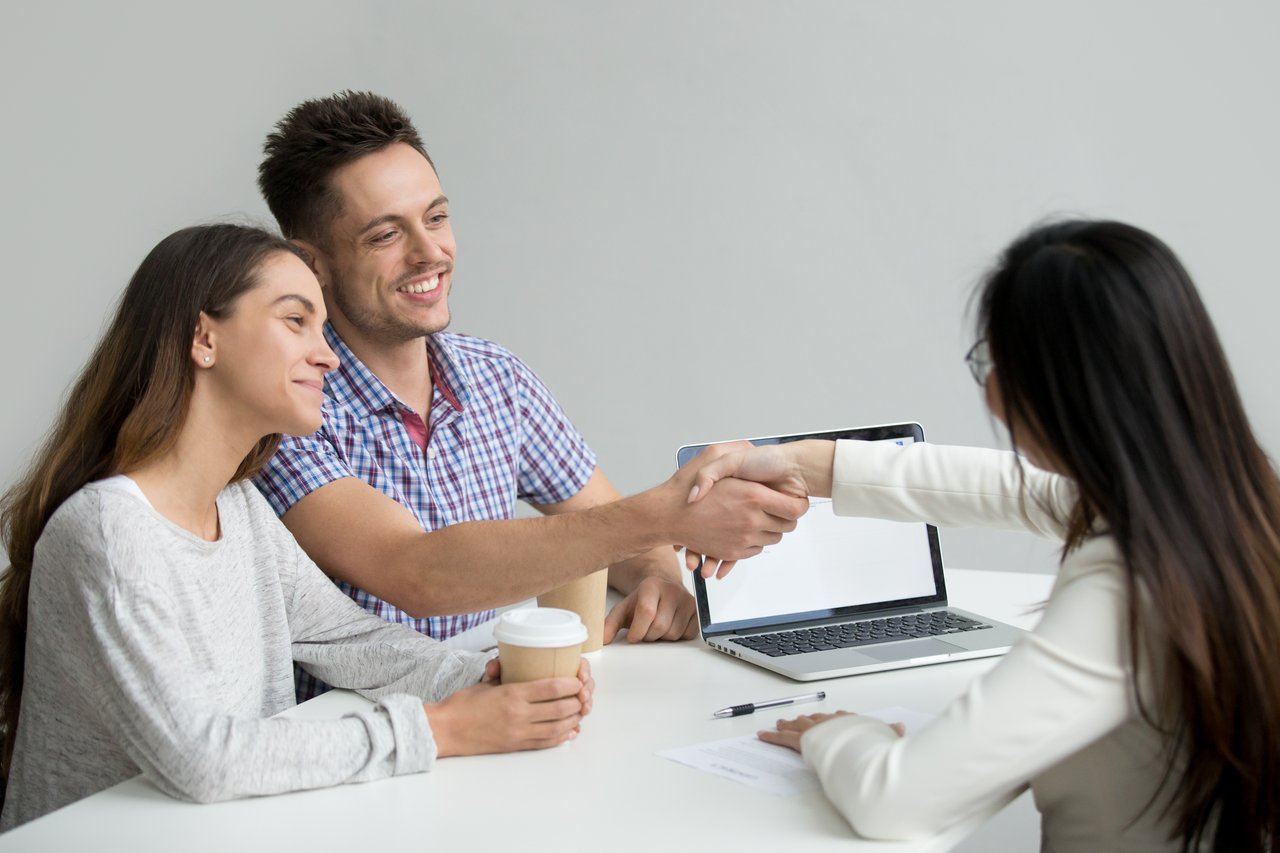 Happy couple meeting with a mortgage consultant to discuss home loan options, symbolizing a successful step in the real estate buying process.