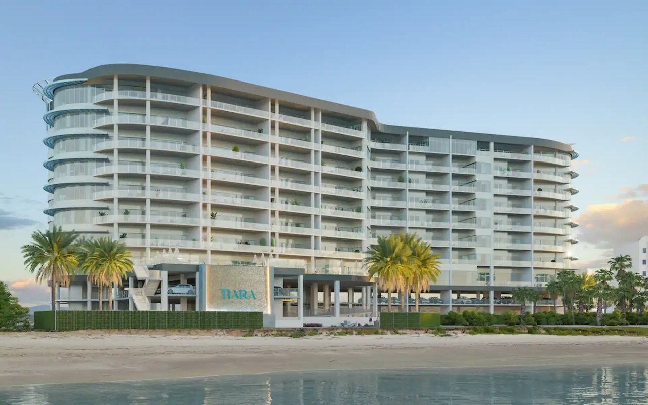 Tiara beachfront condominium with curved balconies, palm trees, and water in the foreground.