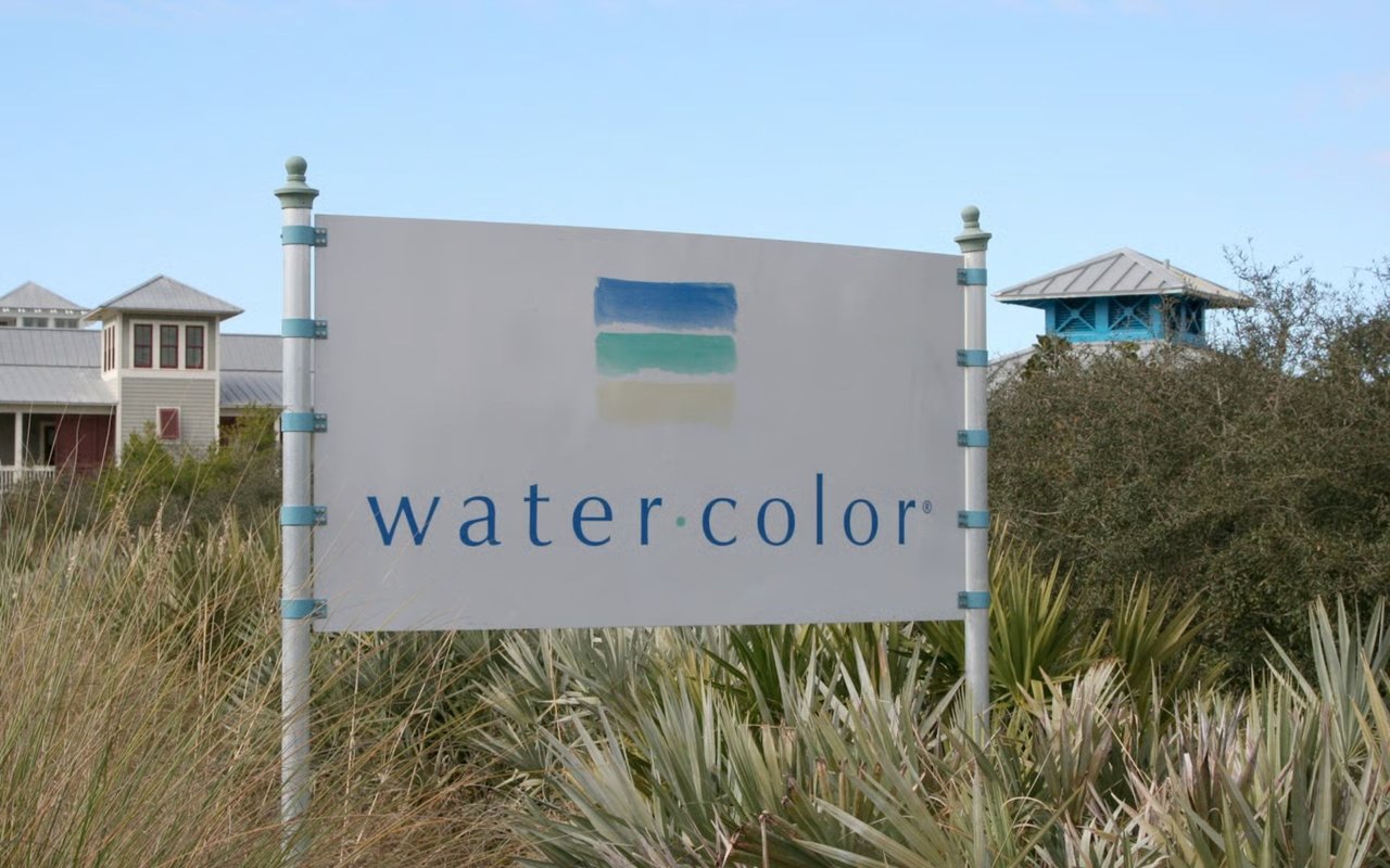 WaterColor community sign surrounded by coastal grasses, with buildings in the background.