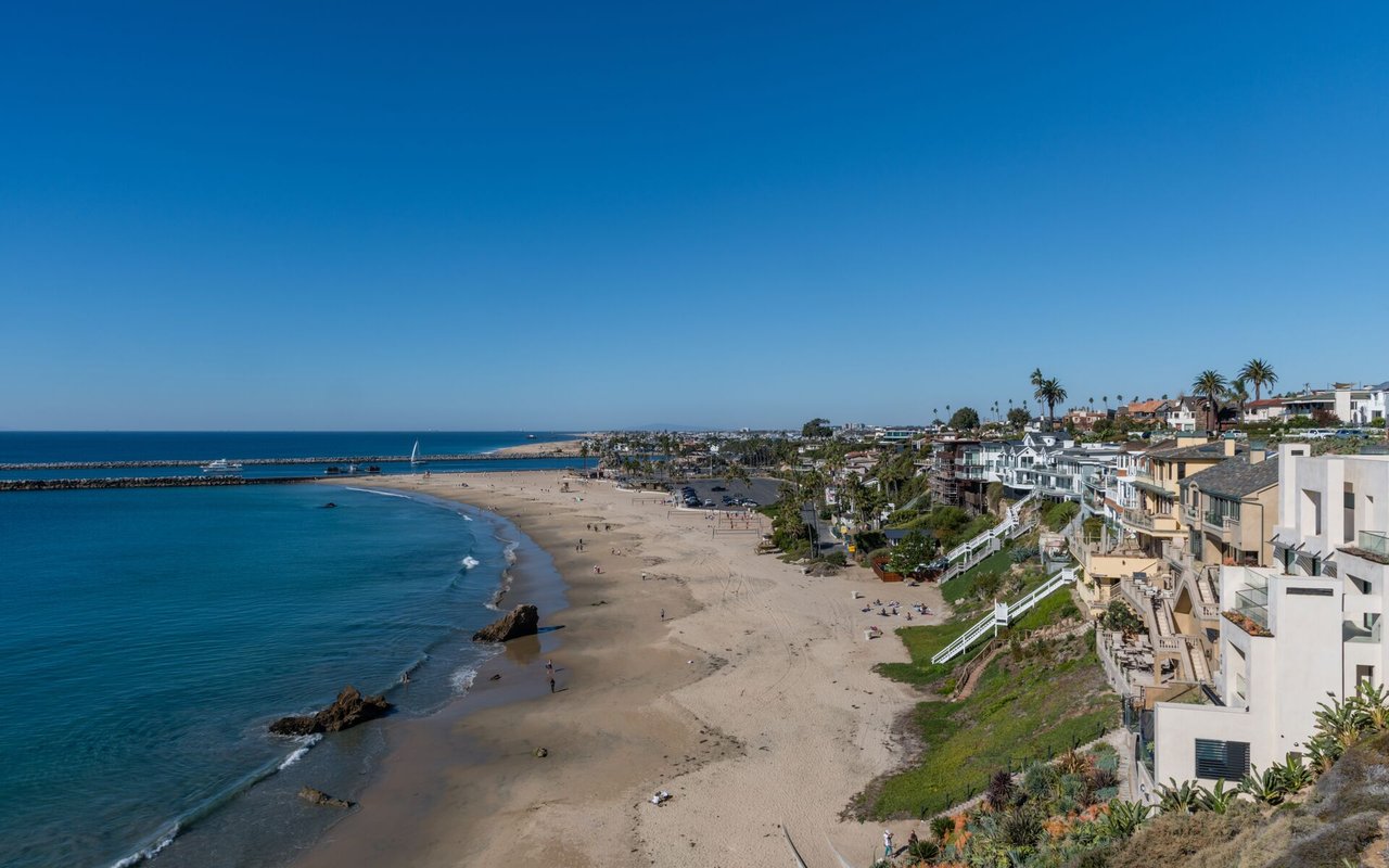 Corona del Mar beach and ocean with coastal homes lining the shore.
