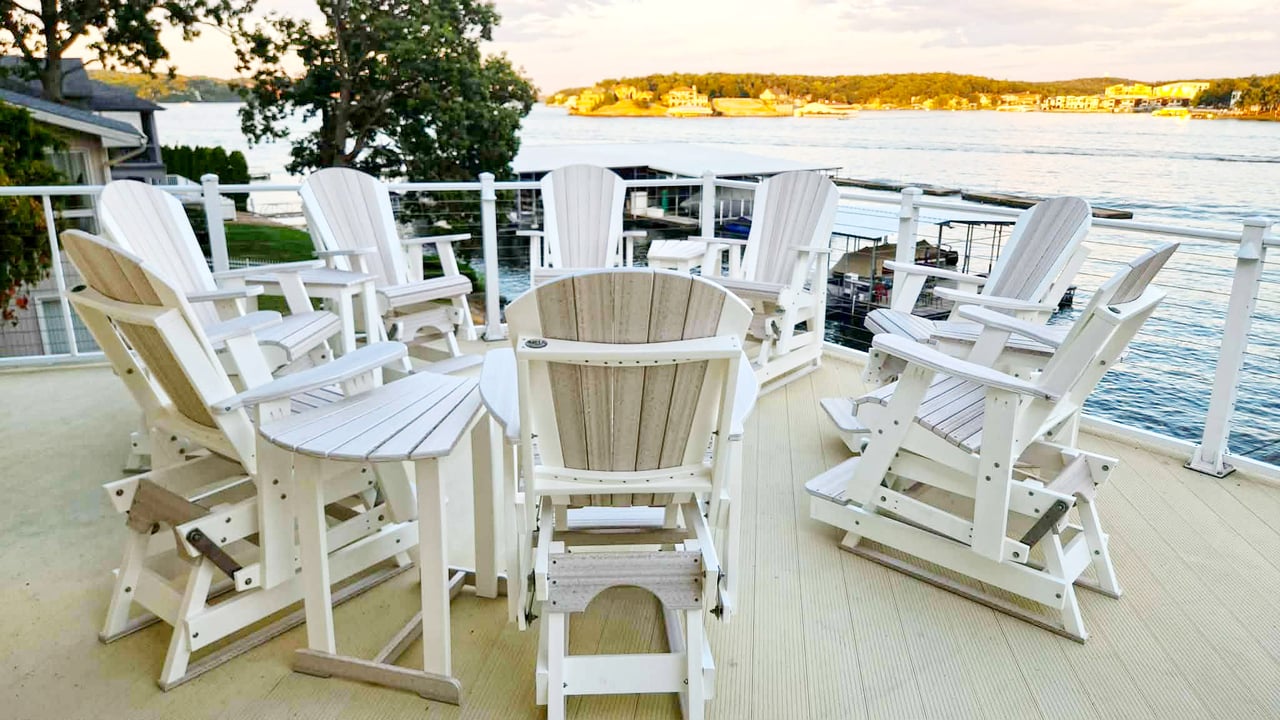 Waterfront deck with white Adirondack chairs overlooking the water at golden hour.