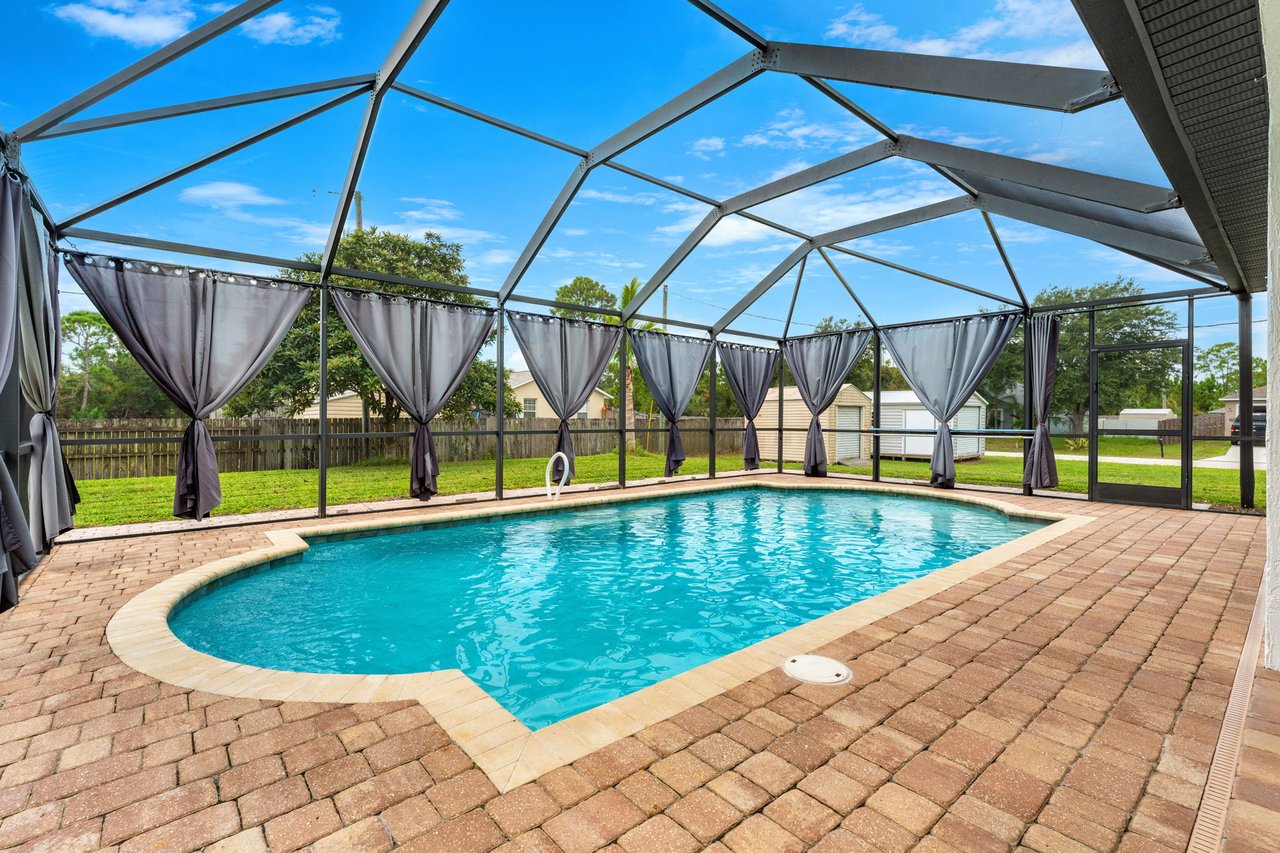Screened swimming pool with expansive paver deck and covered outdoor area