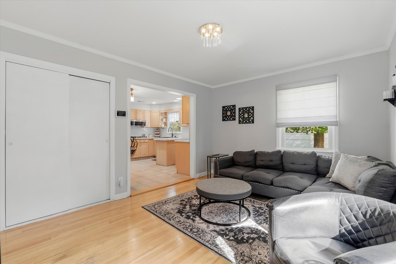 Living room with a gray sectional, patterned rug, and open doorway to a light wood kitchen.