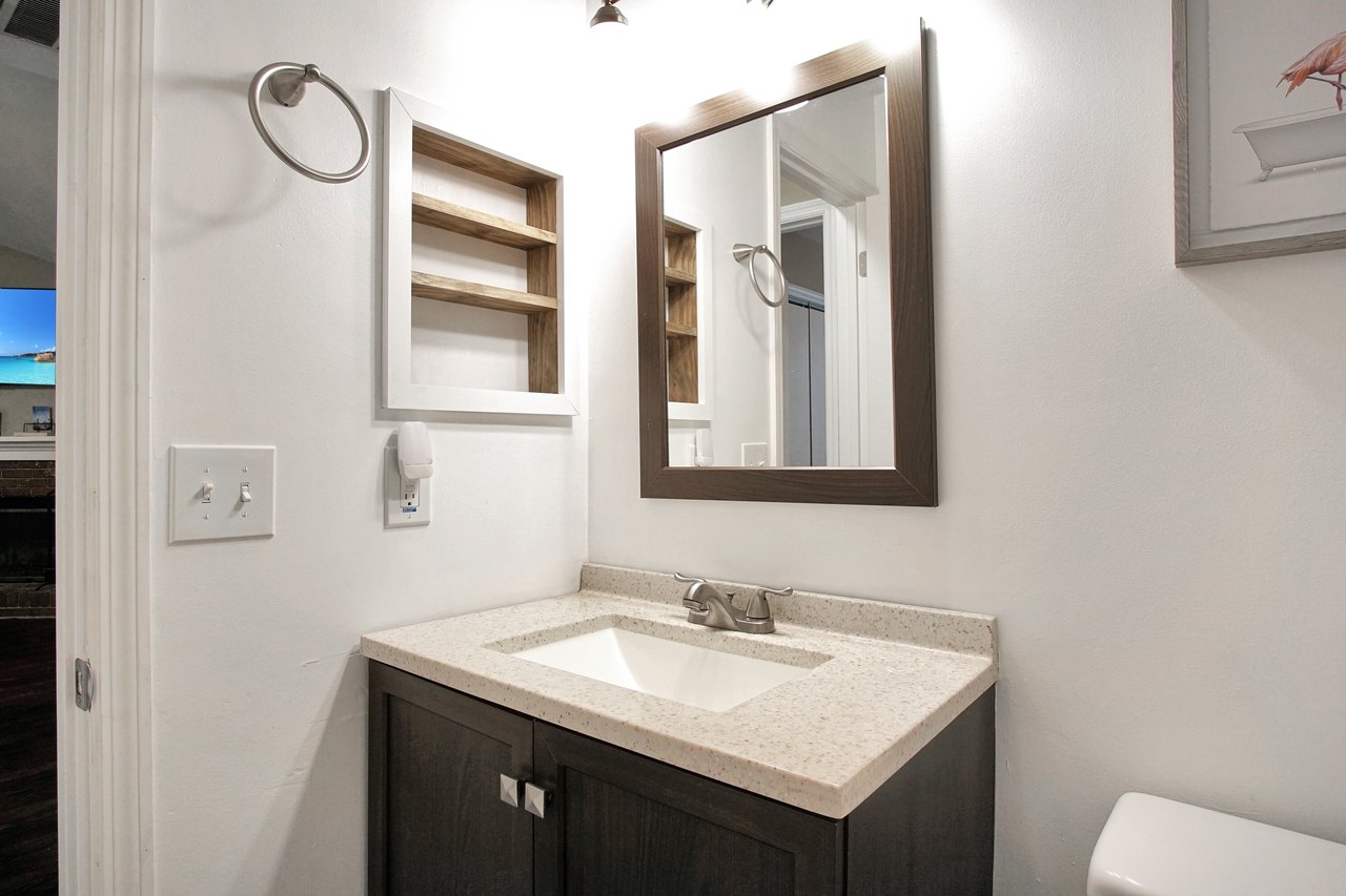 A clean bathroom featuring a sink, toilet, and mirror, showcasing a modern and functional design.