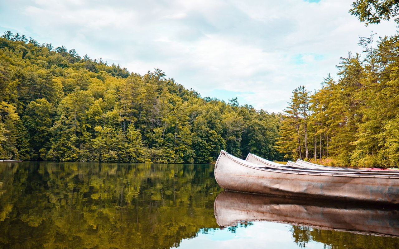 Photo of a glassy lake and canoes in lake glenville north carolina