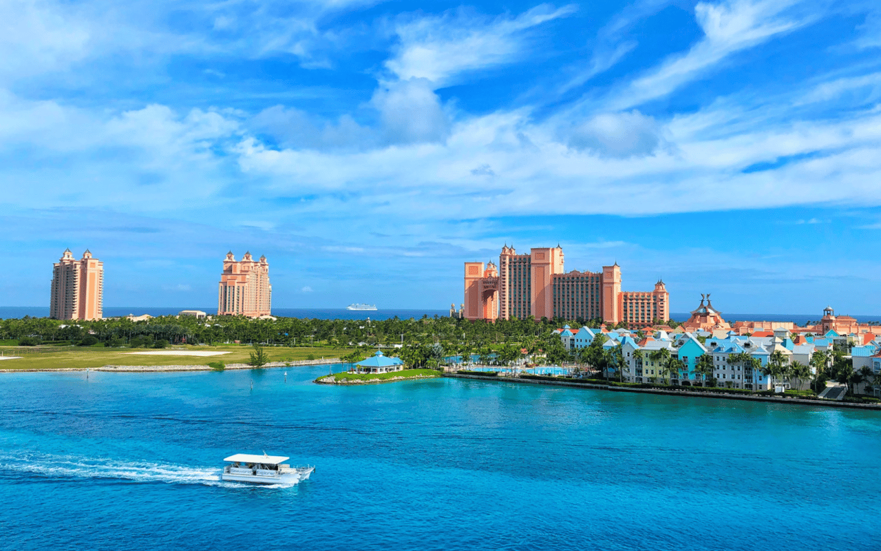 A vibrant turquoise lagoon is traversed by a white speed boat leaving a wake.
