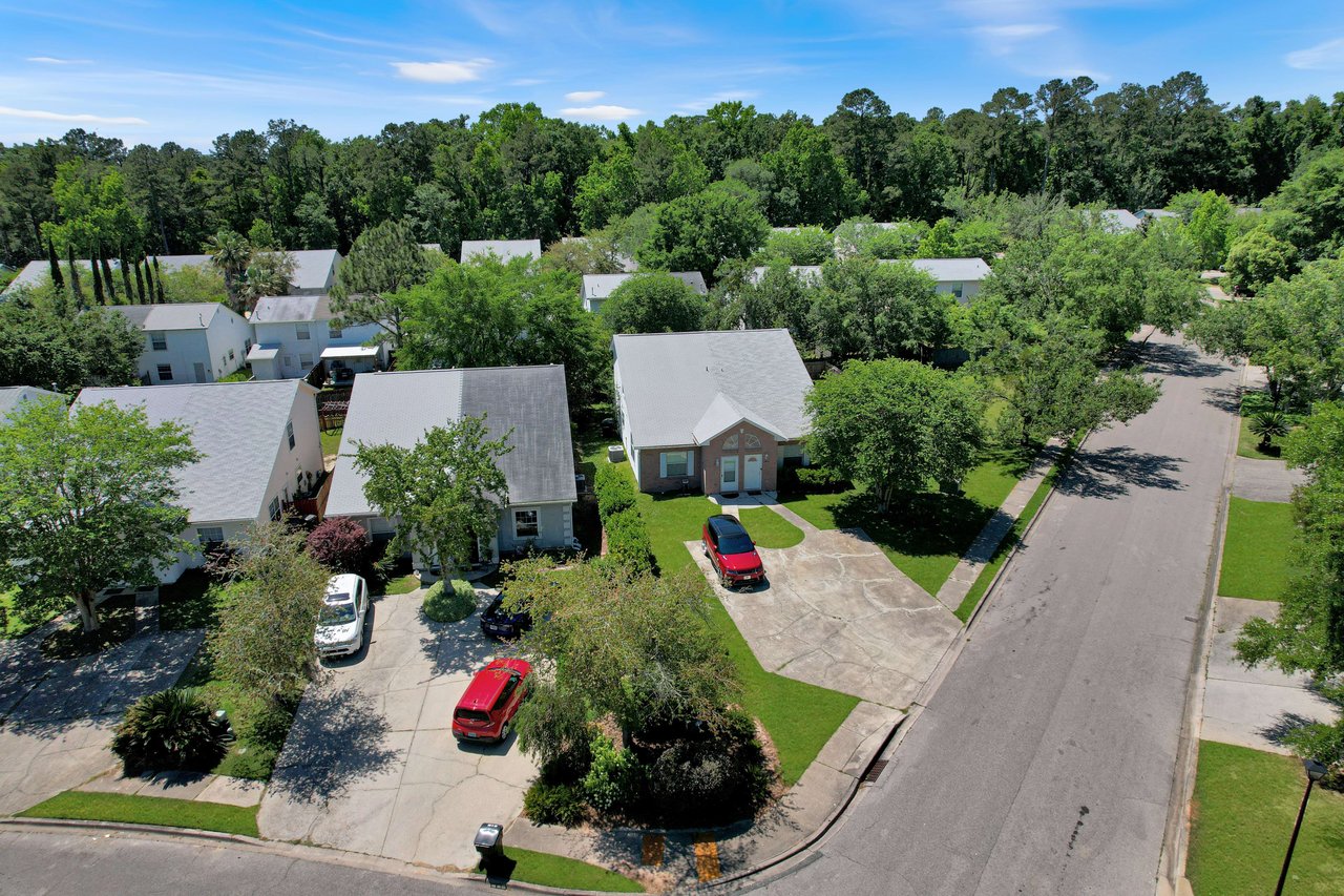 An aerial view of a residential area within the Sawgrass Plantation community, showing houses, streets, and greenery.