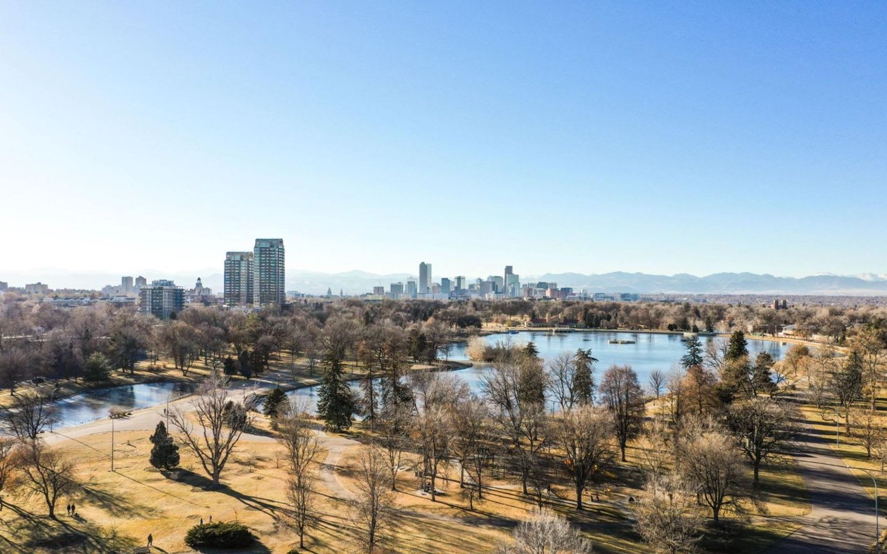 A sprawling park landscape with a large lake reflecting the clear blue sky.