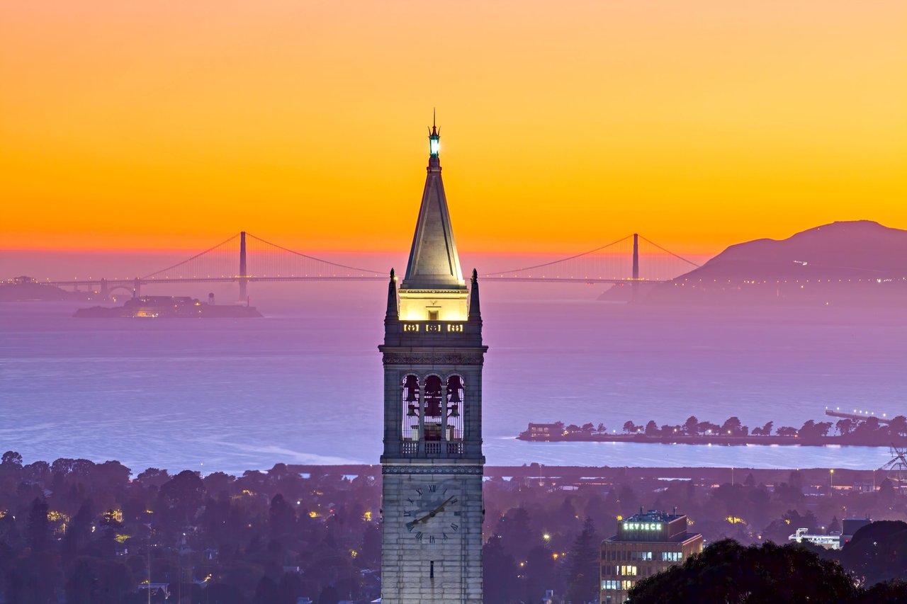 A sunset view of the Berkeley clock tower with the Golden Gate Bridge in the back drop