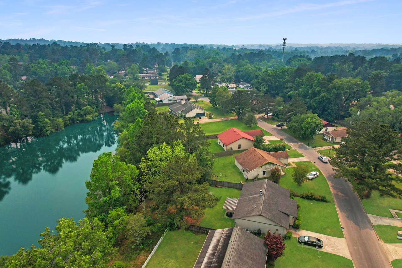 An aerial view focusing on a section of Hartsfield Village near a body of water, highlighting the proximity of houses to natural features.