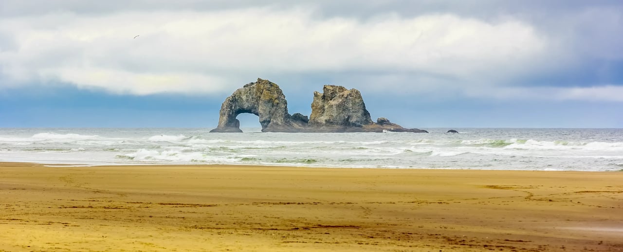 Arch Rock in the ocean on a cloudy day Rockaway Oregon