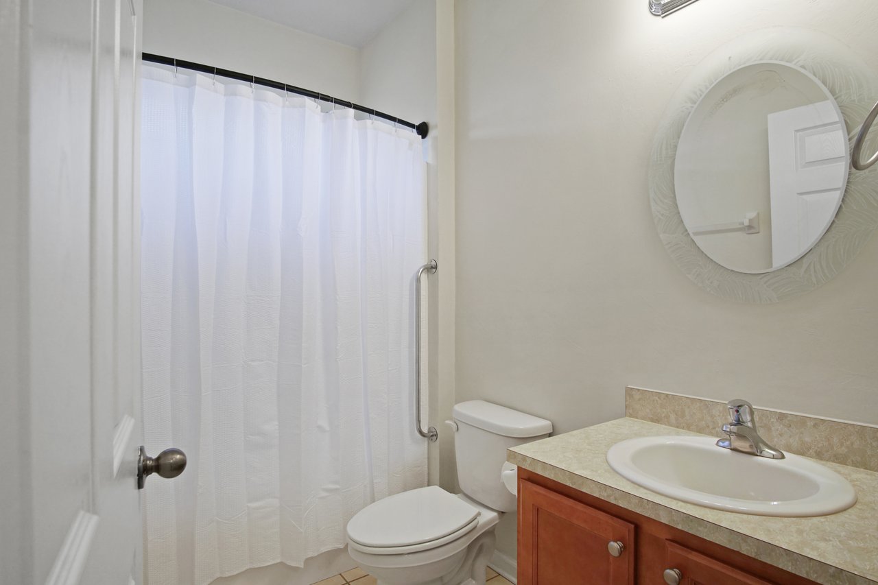 Bathroom at 5441 Hampton Hill Circle, Tallahassee, Florida 32311 featuring vanity with sink, round mirror, and shower-tub combination with curtain.