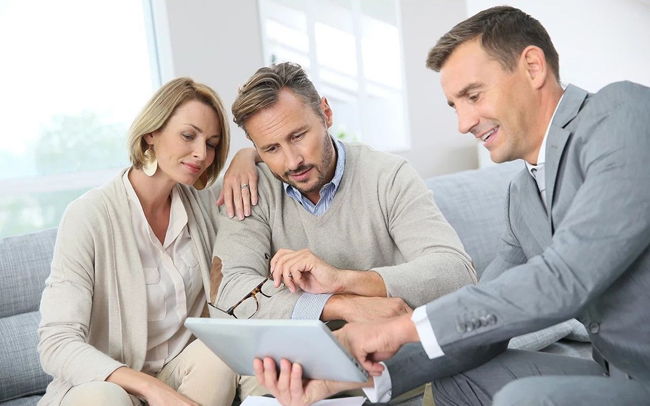 A couple reviews a tablet with a real estate agent.