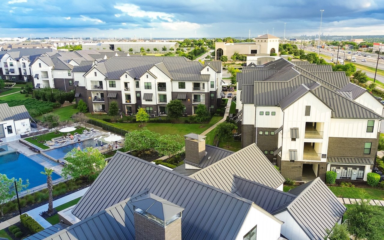 Aerial view of modern apartments surrounding a landscaped courtyard and swimming pool.