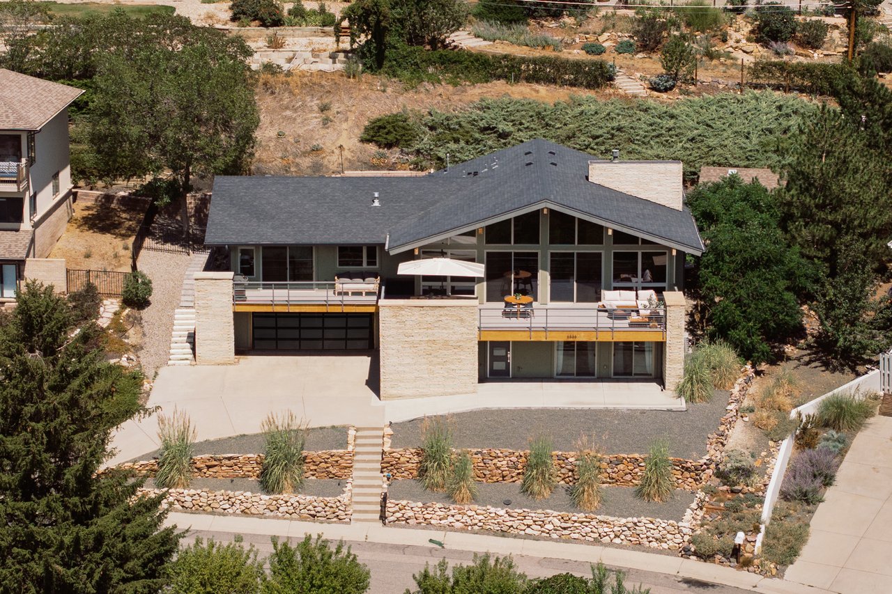 Modern home with broad glass facade, two furnished decks, and stone-edged landscaping