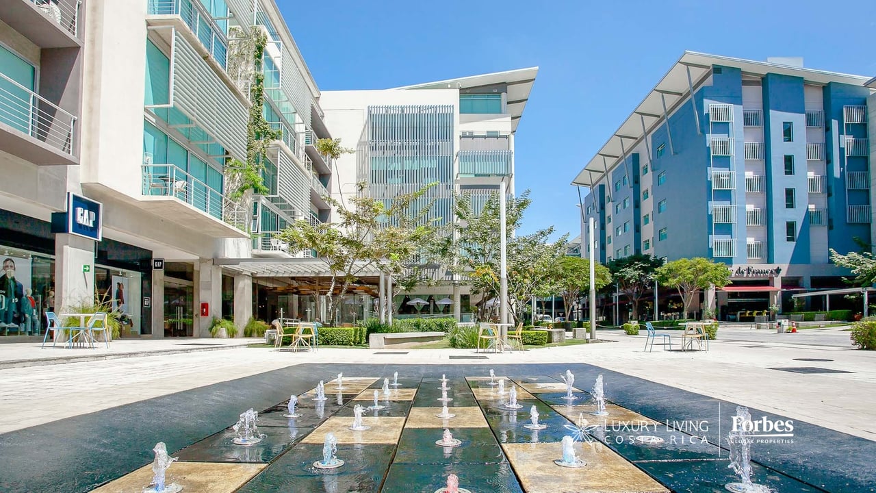 Avenida Escazú plaza with a long fountain, modern buildings, and storefronts.