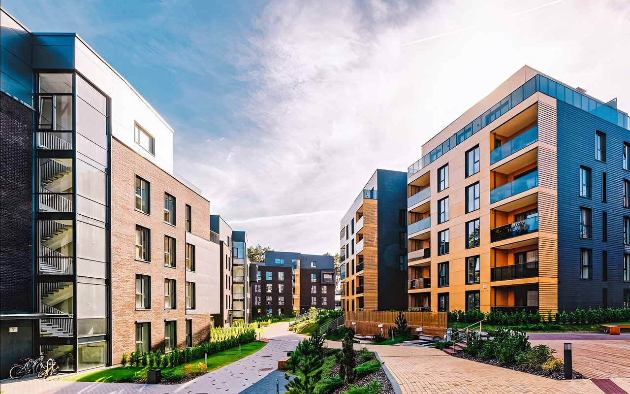 Modern condominium buildings with balconies surrounding a landscaped courtyard.