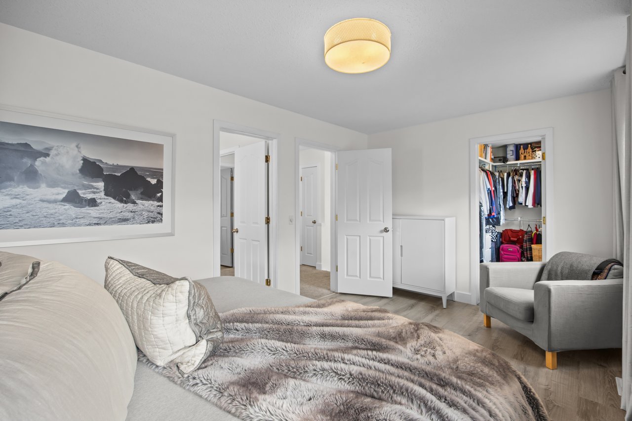 Bedroom with a gray faux-fur bedspread, armchair, and open closet.