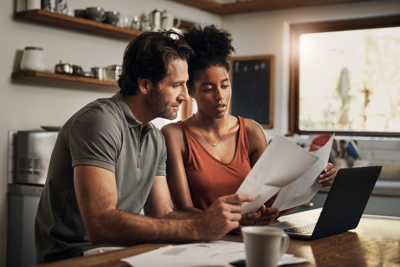 Notebook with refinance notes beside a house model representing a buy now and refinance later strategy