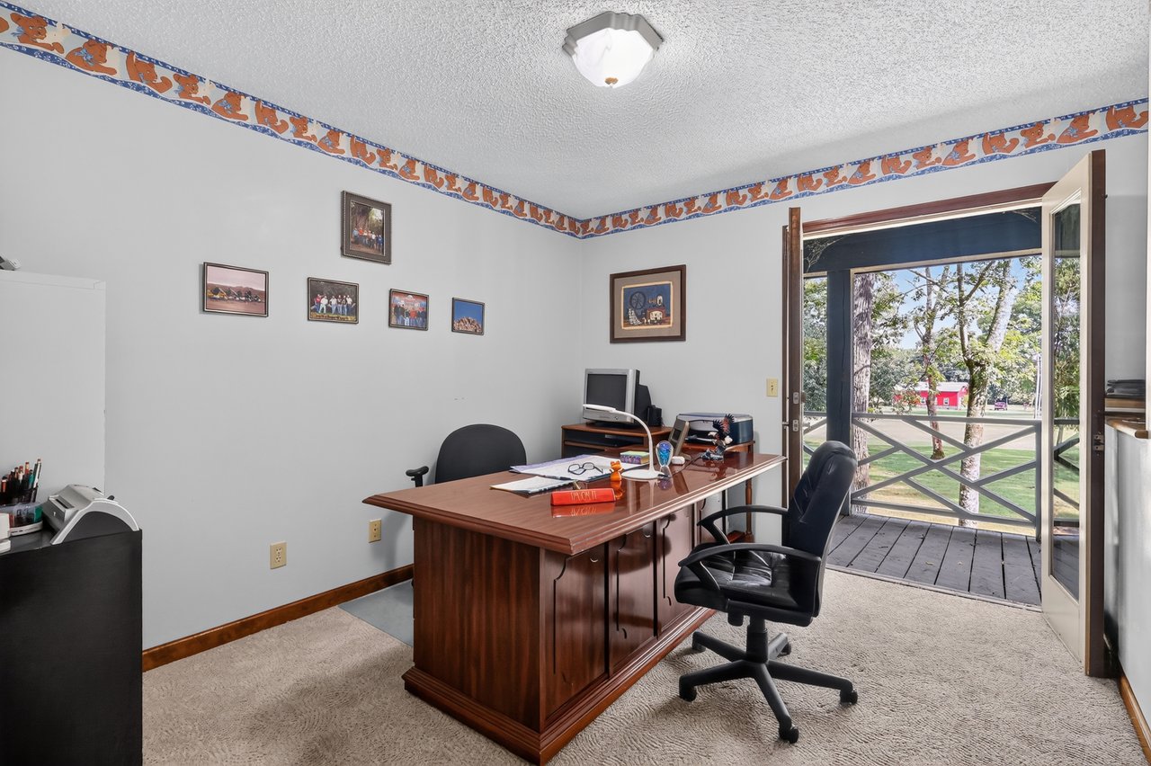 Office with a large wooden desk and an open doorway to a covered porch.