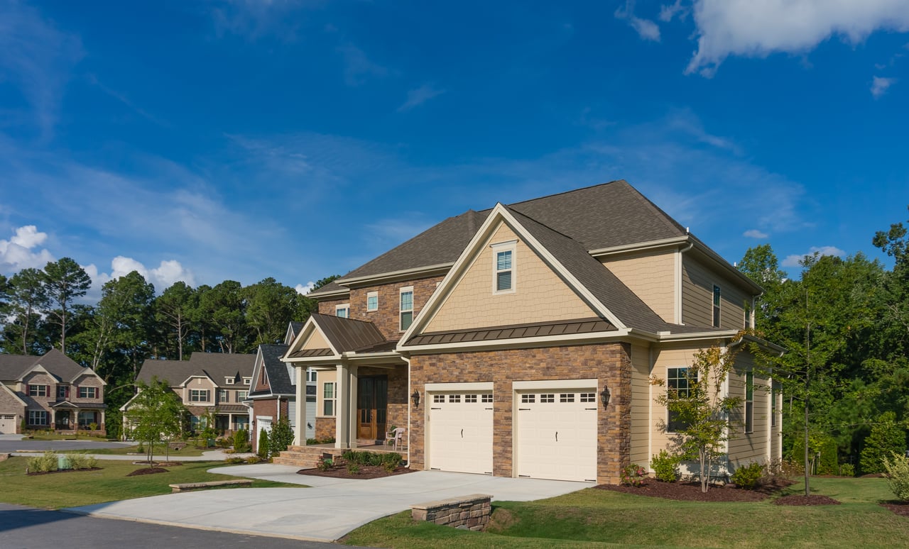 Two-story tan and brick home with a covered entrance and two-car garage.