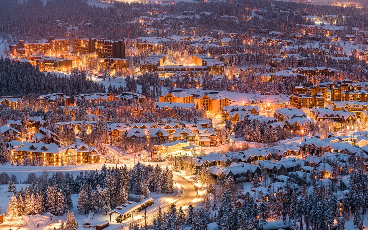 A picturesque winter scene of a mountain town illuminated at night