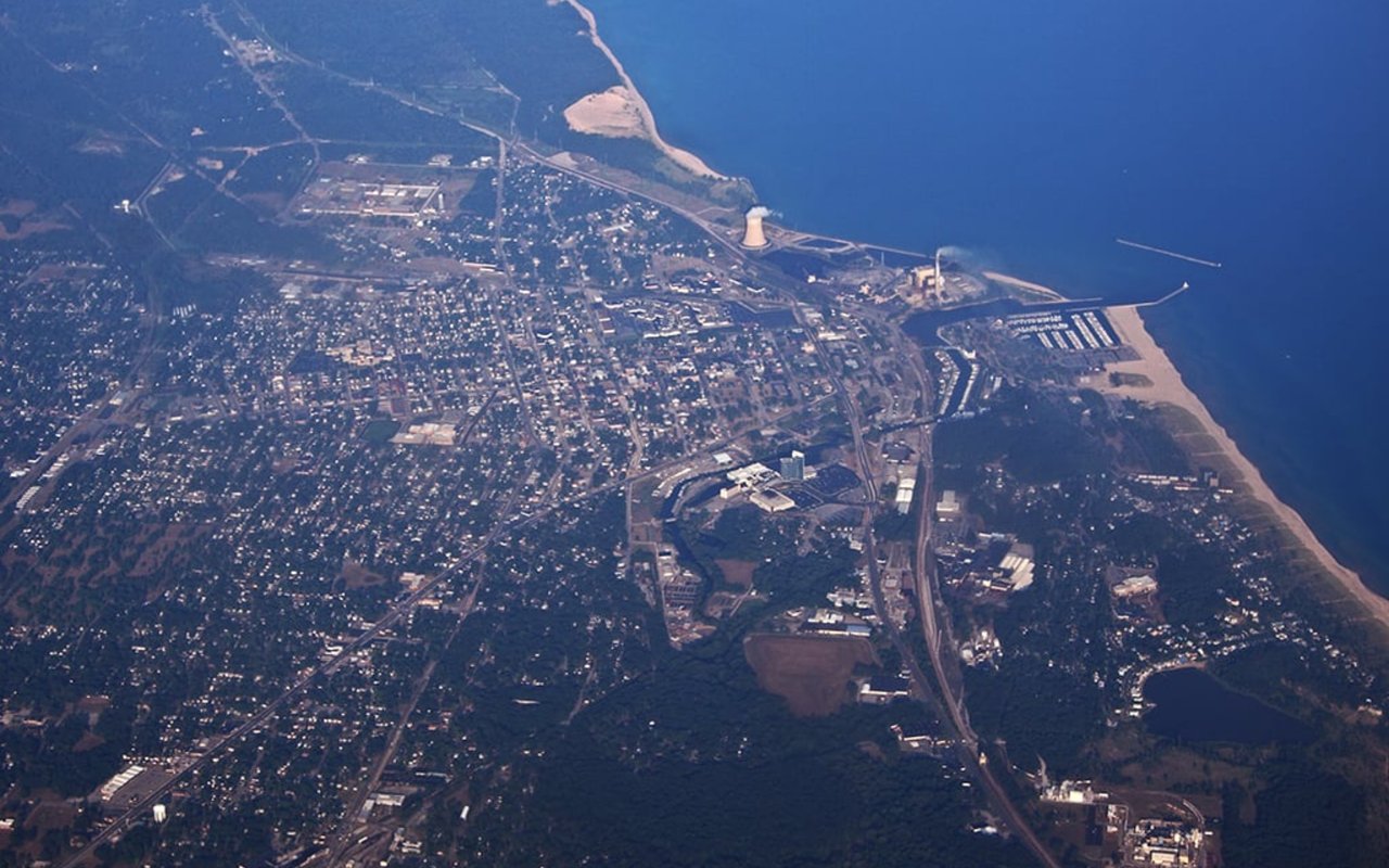 Aerial view of a Michigan lakeshore city with a harbor, beach, and surrounding neighborhoods.