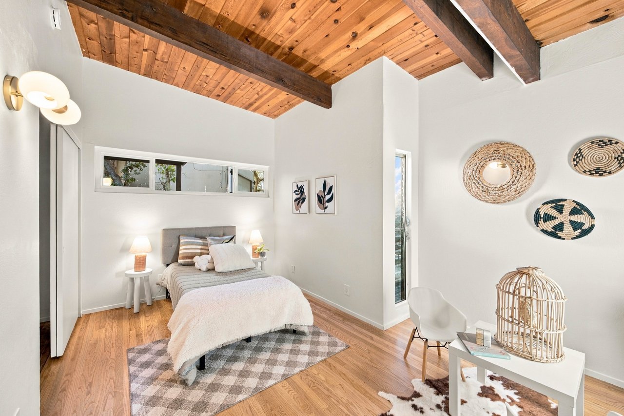Bedroom with a vaulted wood-plank ceiling, exposed beams, and a neatly made bed.