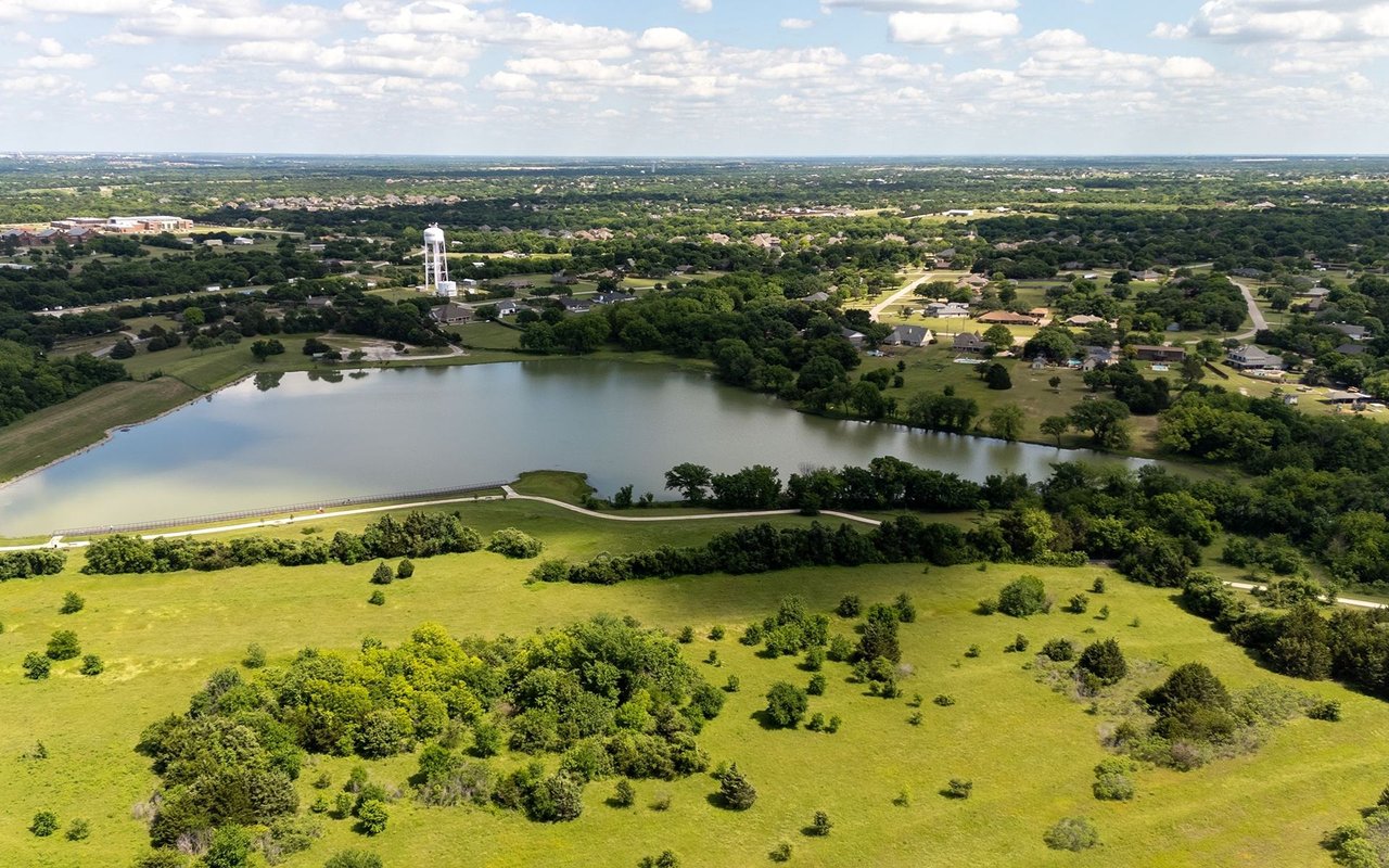 Aerial view of a town and lake bordered by open grassland and trees.