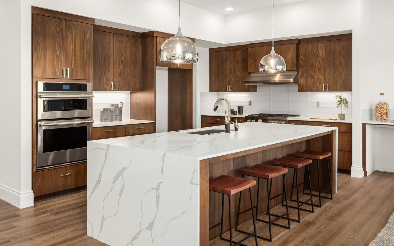 Modern kitchen with walnut cabinets and a large white stone island with bar seating.