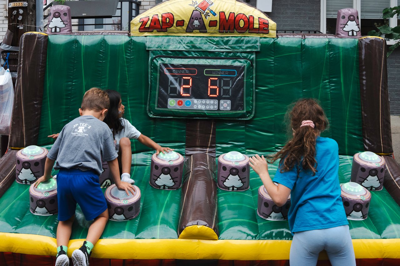 Children play an inflatable Zap-A-Mole game at a neighborhood block party.