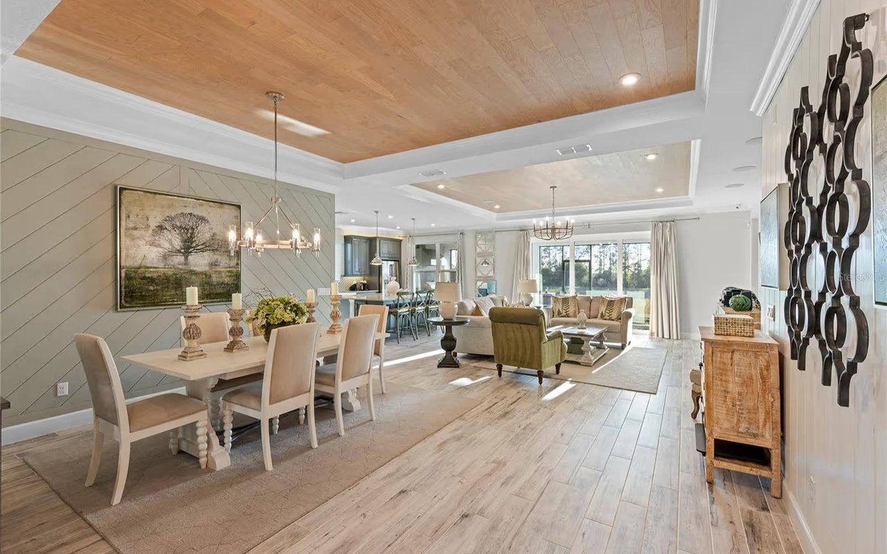 Open-plan dining and living room with a wood-paneled ceiling and sliding glass doors.