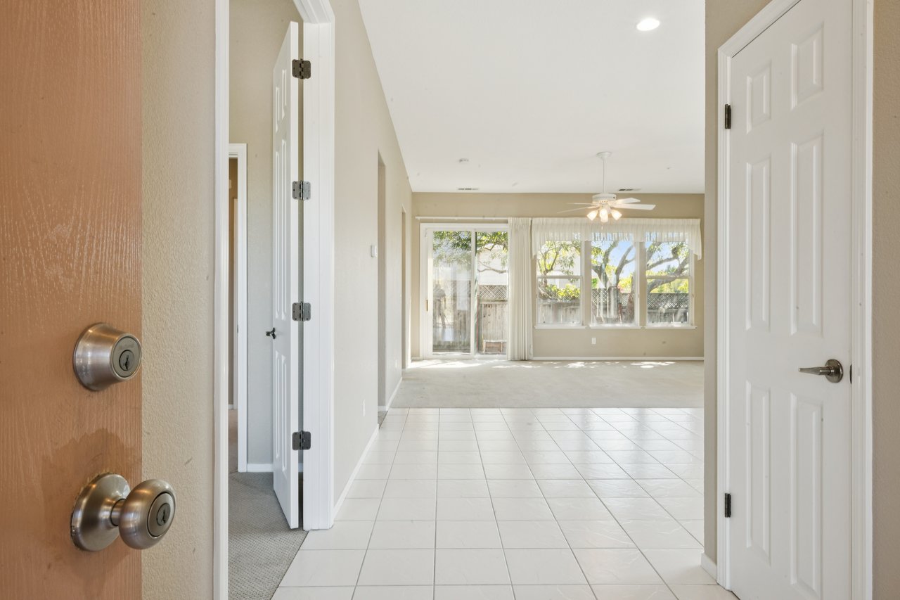 Tiled entryway opening into an unfurnished living room with large windows and a sliding glass door.