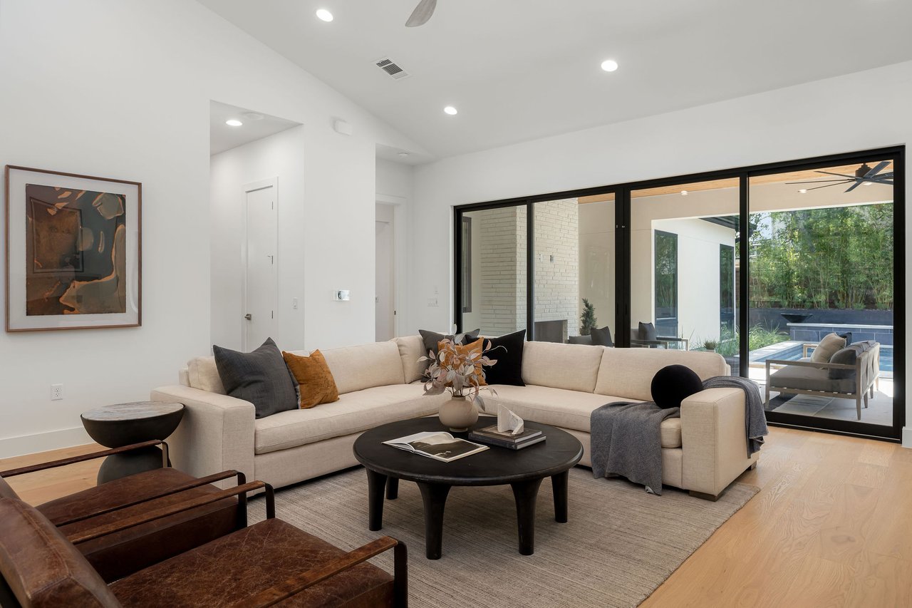 Great room at 1001 Bluebonnet Ln in Zilker, Austin, with a sectional sofa and a full wall of glass overlooking the pool and patio.
