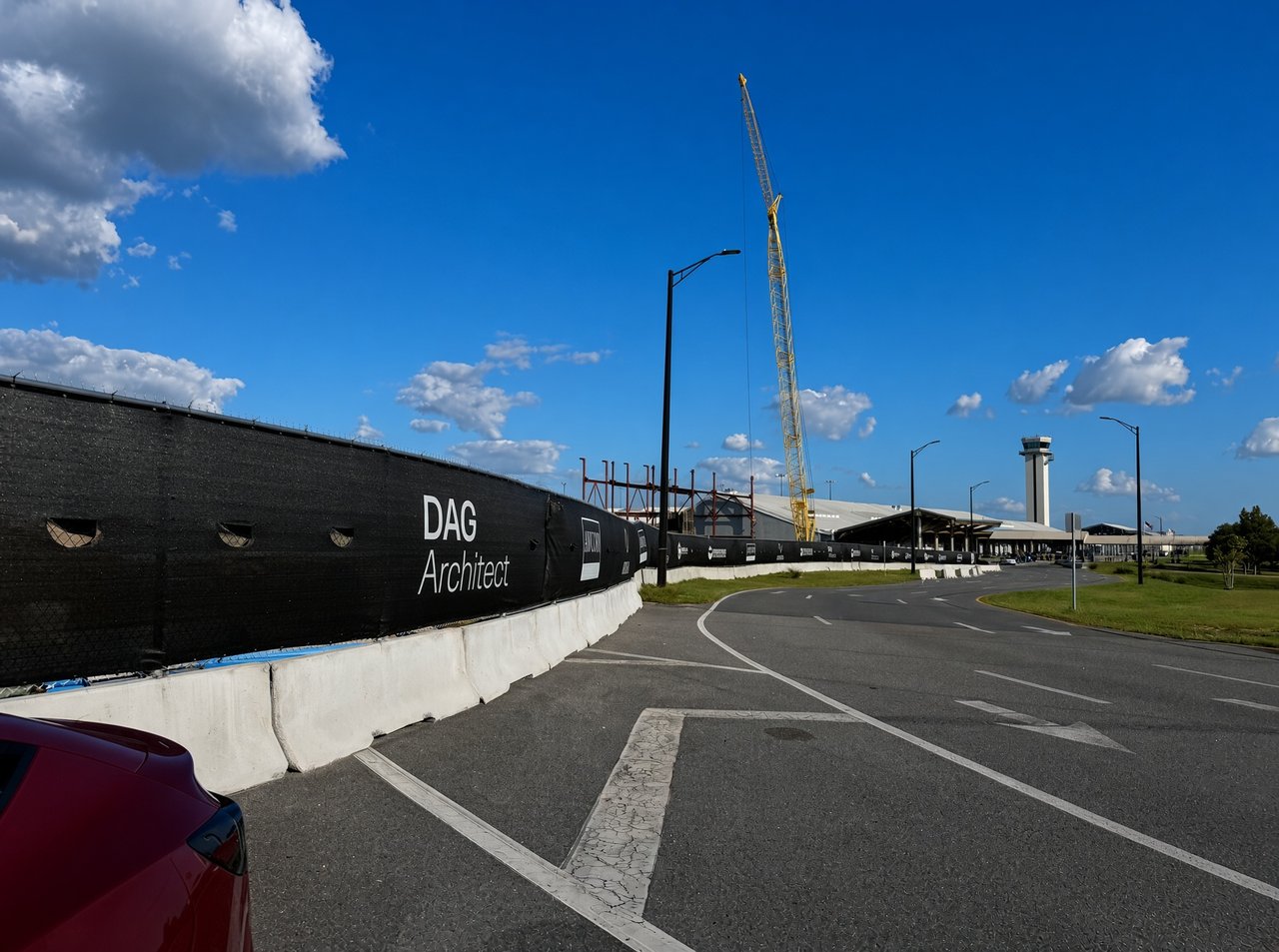Airport construction site showing a yellow crane, the ECP control tower, and a black fence reading DAG Architect.