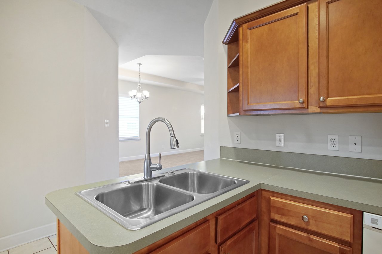 Kitchen view from 5441 Hampton Hill Circle, Tallahassee, Florida 32311 showing double sink, wood cabinetry, and open layout to dining area.