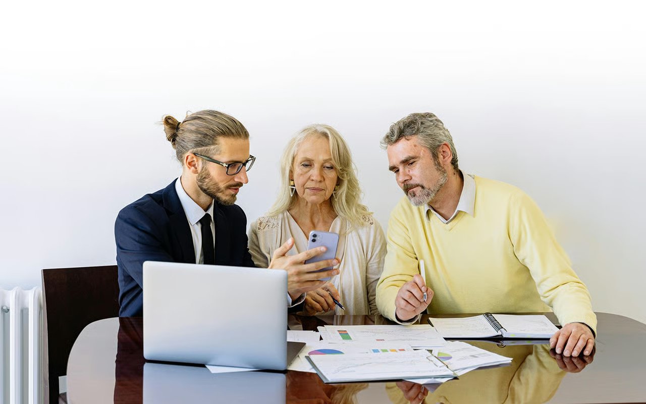 Real estate agent and older couple reviewing offer documents at a table