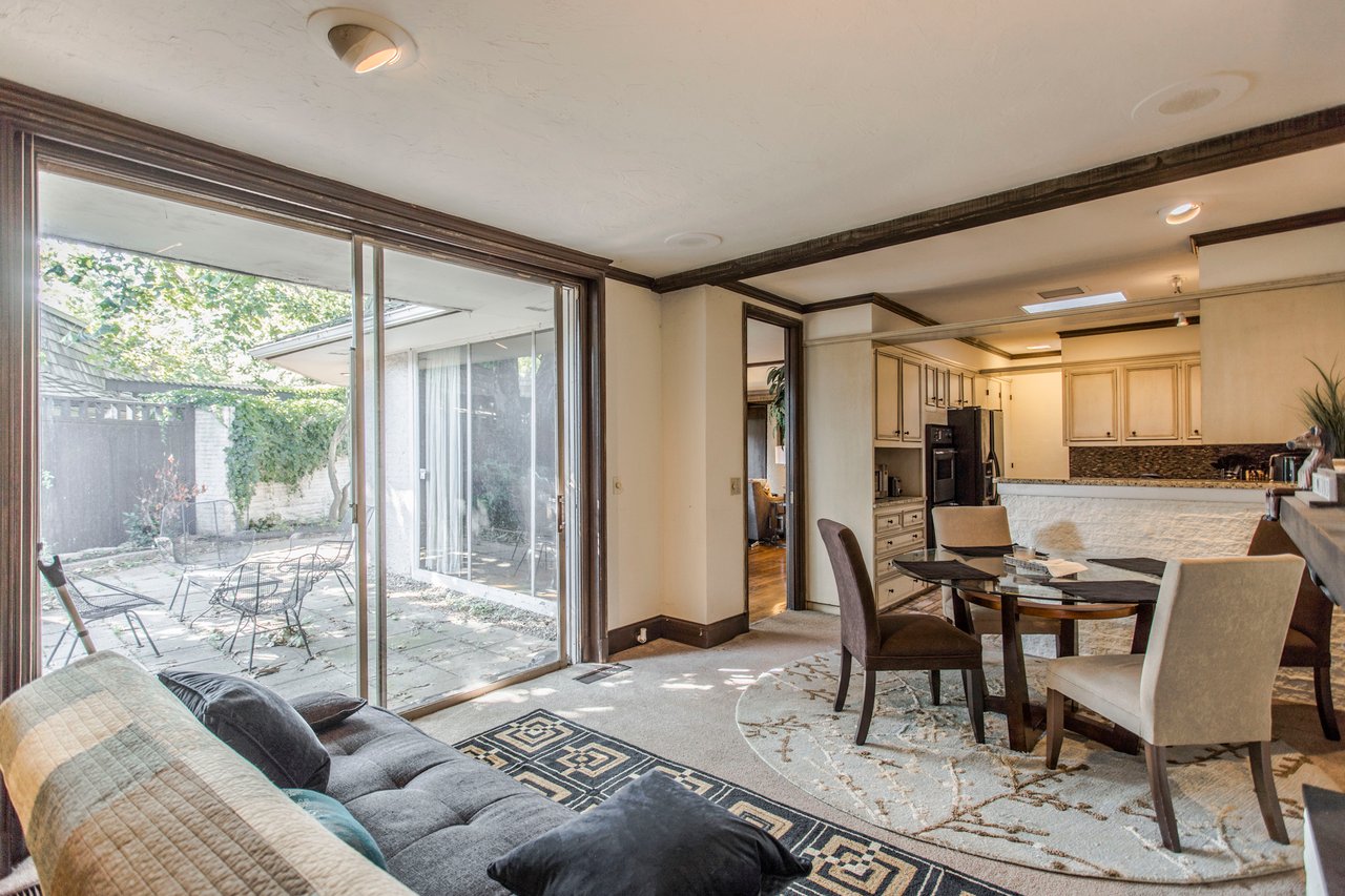 Living and dining area with a sliding glass door opening onto a paved patio.