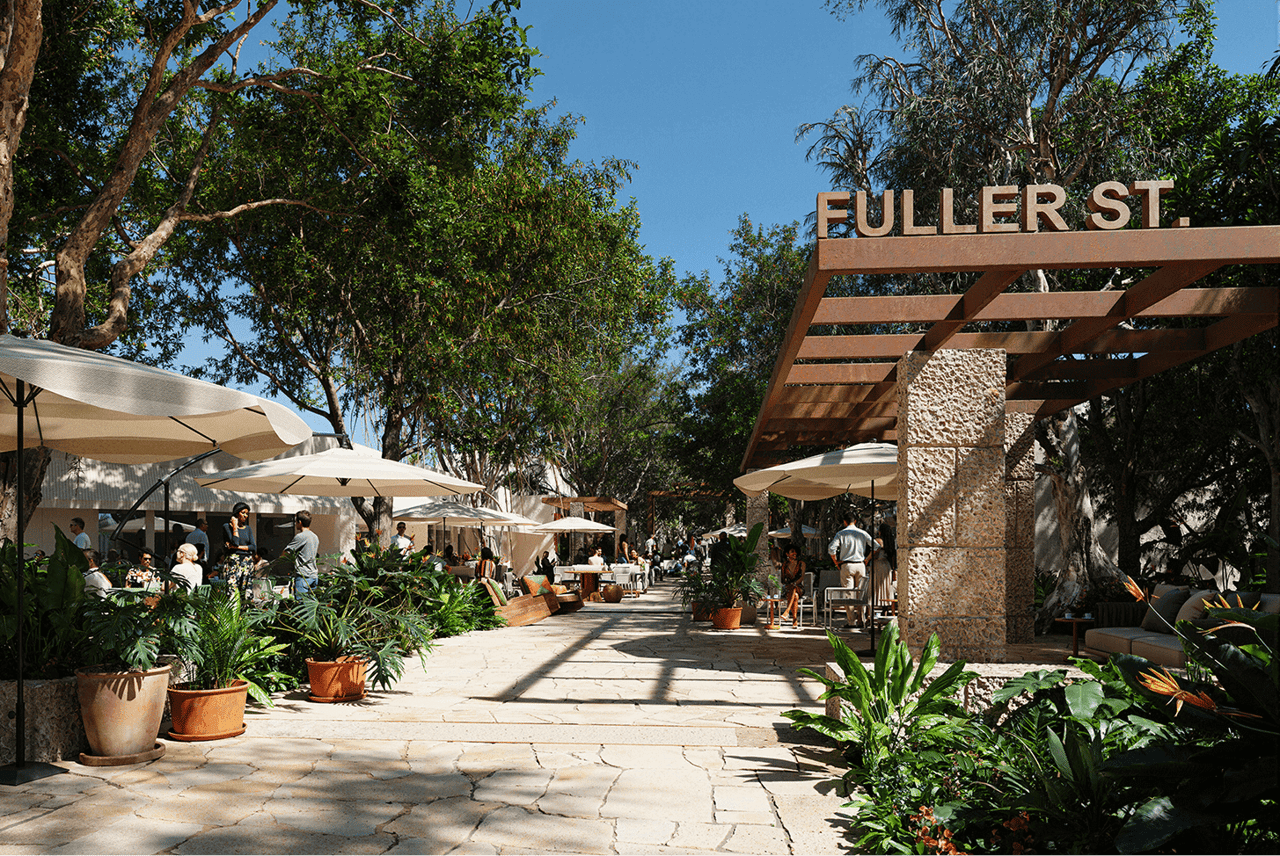 Landscaped pedestrian plaza with shaded café seating and a prominent Fuller St. sign.