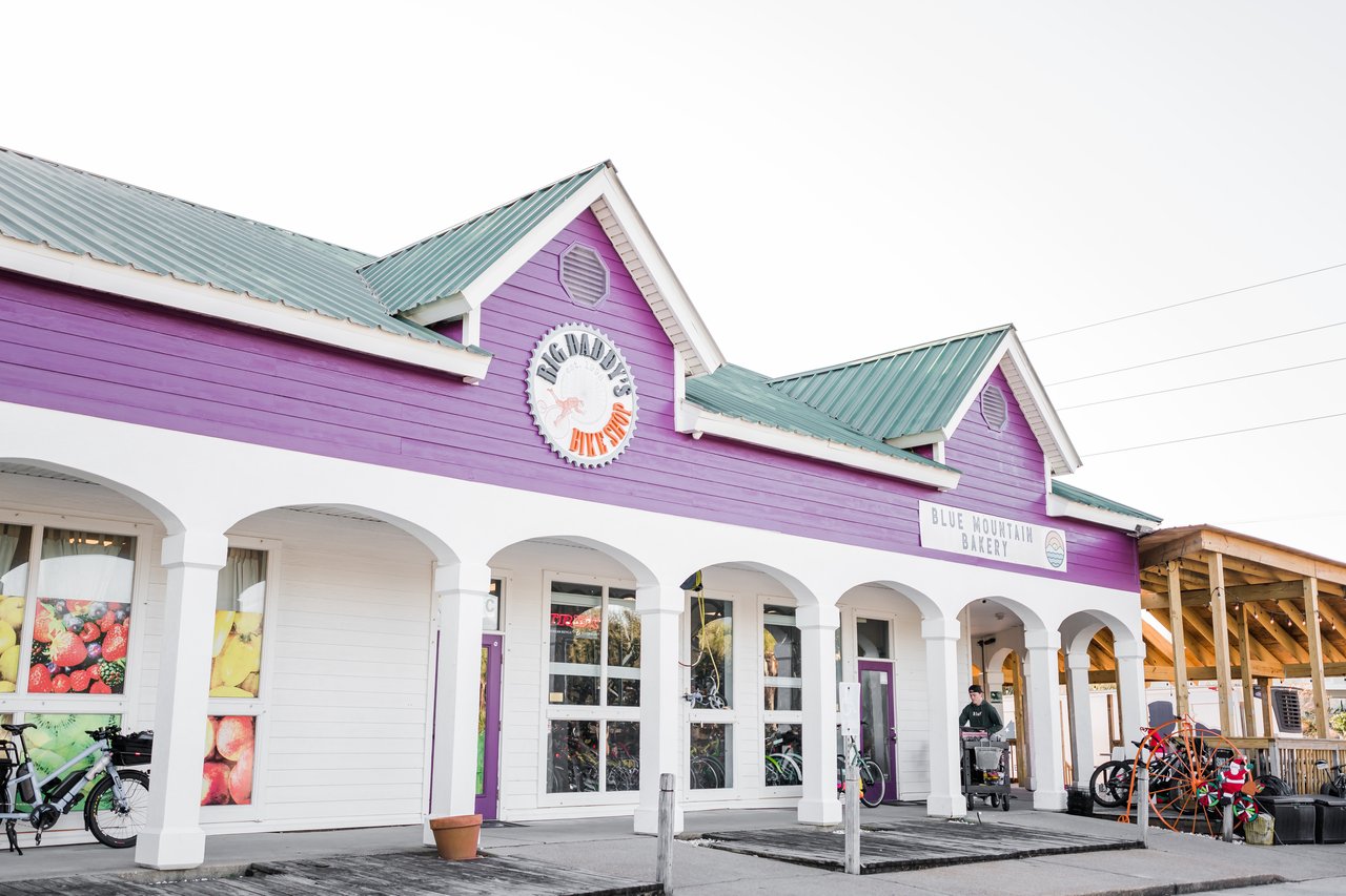 Vibrant purple market-bakery building with a white columned arcade and beach bikes parked out front at Blue Mountain Beach on 30A, Florida